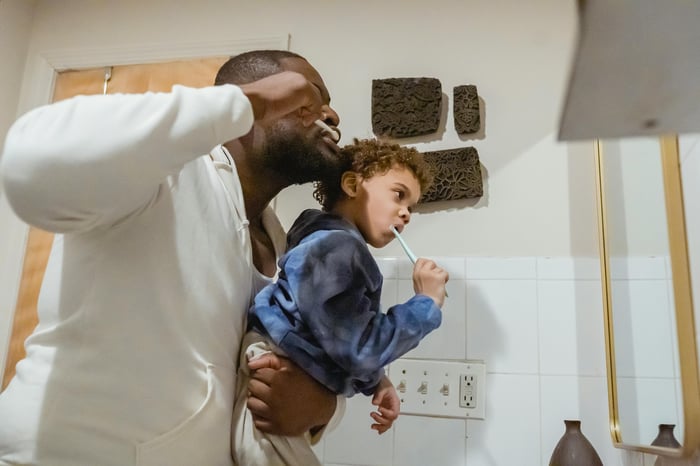 Un padre y un hijo cepillándose los dientes frente al espejo