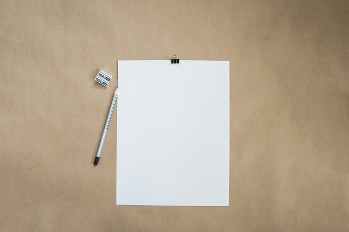 A blank piece of paper, a pencil and a sharpener